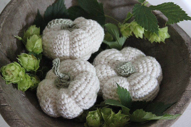 Calabazas tejidas a crochet de lana blanca y verde en un cuenco.